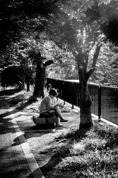 A woman reads by the canal in Kyoto, Japan
