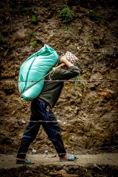 A porter carries rice through a village, Nepal